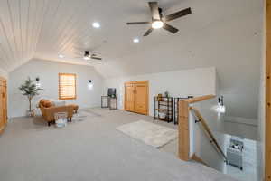 Sitting room featuring ceiling fan, vaulted ceiling, light carpet, and wood walls