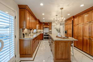 Kitchen with backsplash, a center island, custom exhaust hood, an inviting chandelier, and hanging light fixtures