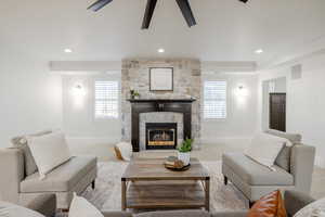 Carpeted living room featuring ornamental molding and a stone fireplace