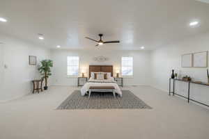 Carpeted bedroom with ceiling fan, multiple windows, and ornamental molding