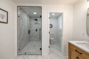 Bathroom with toilet, a shower with door, and vanity