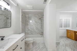 Full bathroom featuring tiled shower / bath, vanity, toilet, and a textured ceiling