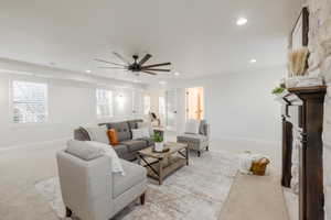 Living room with ceiling fan, light colored carpet, and crown molding