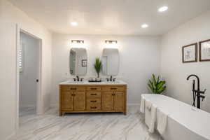 Bathroom featuring a textured ceiling, a bathtub, and vanity