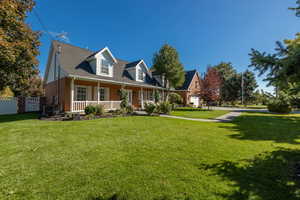 New england style home featuring a front lawn and a porch