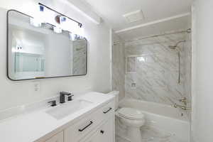 Full bathroom featuring tiled shower / bath, vanity, and toilet