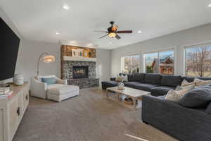 Carpeted living room with ceiling fan and a fireplace