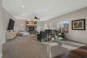 Living room featuring ceiling fan, a fireplace, and carpet floors