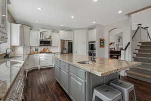 Kitchen with appliances with stainless steel finishes, a kitchen breakfast bar, white cabinetry, and a center island with sink