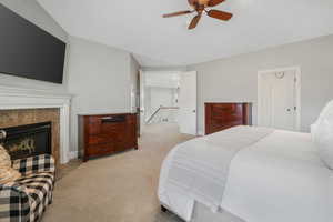 Carpeted bedroom featuring ceiling fan and a tile fireplace