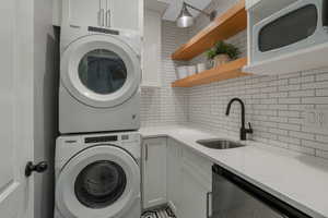 Clothes washing area with stacked washer and clothes dryer and sink