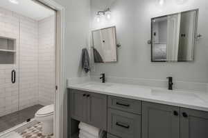 Bathroom featuring toilet, vanity, and a shower with shower door