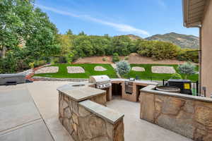 View of patio / terrace with area for grilling, central air condition unit, grilling area, a mountain view, and a hot tub