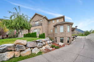 View of front of home with a mountain view, a balcony, and a front yard