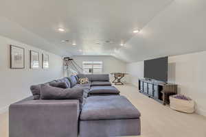 Carpeted living room with a textured ceiling and vaulted ceiling