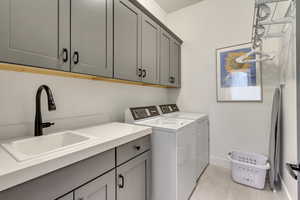 Washroom with sink, cabinets, washer and dryer, and light tile patterned floors