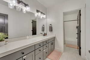 Bathroom with tile patterned flooring, shower / tub combo with curtain, and vanity