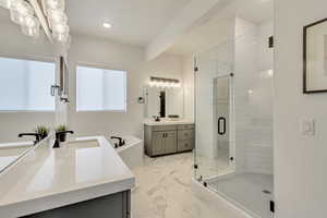 Bathroom featuring vanity, beamed ceiling, and plus walk in shower