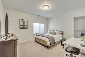 Bedroom with a textured ceiling and light carpet