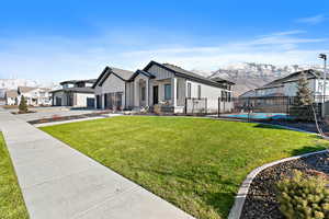 View of front facade featuring a front yard, a fenced in pool, a garage, and a mountain view