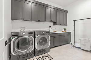 Laundry room with cabinets, separate washer and dryer, and sink