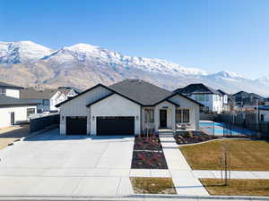 Modern farmhouse featuring a front lawn, a mountain view, and a garage