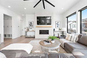 Living room featuring ceiling fan, a fireplace, and light hardwood / wood-style flooring