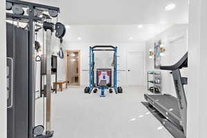 Workout area with a textured ceiling and light colored carpet could be a theatre room