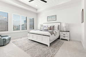 Bedroom featuring ceiling fan, light colored carpet, and a raised ceiling