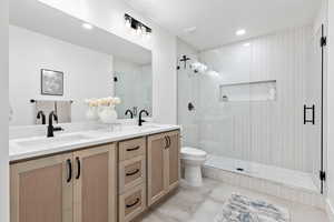 Bathroom featuring a shower with shower door, vanity, toilet, and a textured ceiling