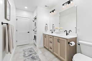 Bathroom featuring stacked washer / dryer, toilet, and vanity