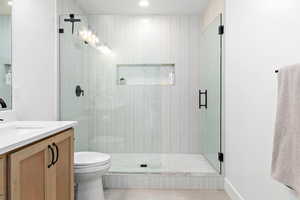 Bathroom featuring toilet, tile patterned flooring, an enclosed shower, and vanity