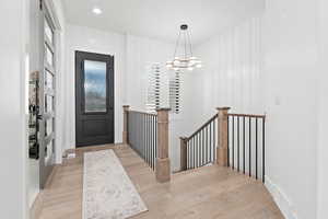 Foyer with light wood-type flooring and an inviting chandelier