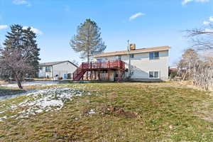 Rear view of property featuring a wooden deck and a yard