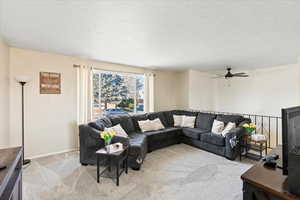 Living room with light carpet, ceiling fan, and a textured ceiling