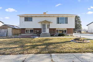 Bi-level home with a front lawn and a shed