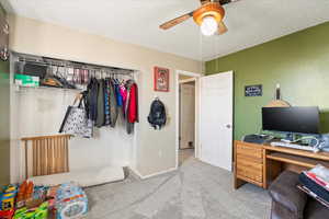 Carpeted bedroom featuring ceiling fan and a textured ceiling