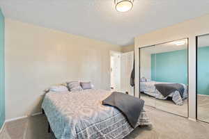 Bedroom featuring a textured ceiling, multiple closets, and carpet