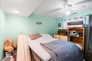 Carpeted bedroom featuring ceiling fan and a textured ceiling