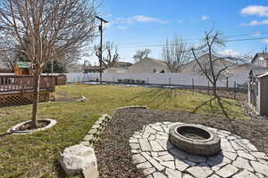 View of yard featuring a wooden deck, a patio area, a playground, and a fire pit