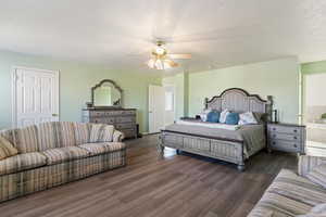 Bedroom with ceiling fan, ensuite bath, dark wood-type flooring, and a textured ceiling