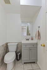 Bathroom with tile patterned floors, tile walls, toilet, and vanity