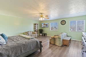 Bedroom with ceiling fan, light wood-type flooring, and a textured ceiling