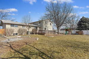 Rear view of house featuring a lawn, a fire pit, cooling unit, a playground, and a deck