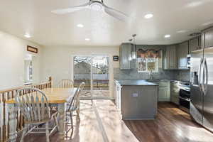 Kitchen featuring decorative light fixtures, stainless steel appliances, dark stone countertops, backsplash, and dark hardwood / wood-style floors