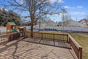 Wooden terrace featuring a lawn and a playground