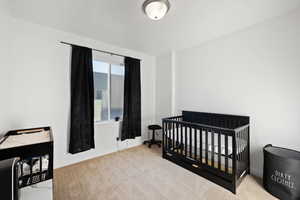 Bedroom with a nursery area and light colored carpet