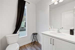 Bathroom with wood-type flooring, vanity, and toilet