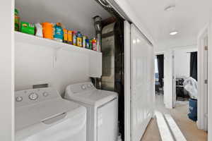 Clothes washing area featuring light carpet and washing machine and clothes dryer