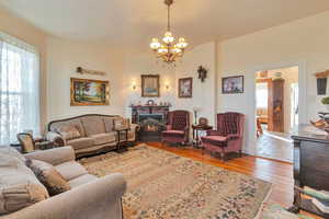 Living room featuring light wood-type flooring, a chandelier, and a healthy amount of sunlight